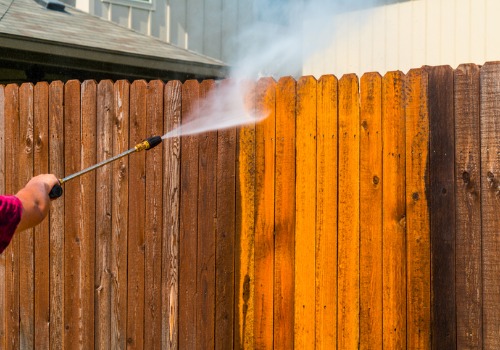 Man pressure washing fence to keep it clean and increase its longevity
